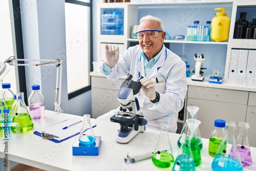 Senior man wearing scientist uniform holding sample at laboratory