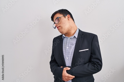 Young hispanic man with down syndrome wearing business style with hand on stomach because nausea, painful disease feeling unwell. ache concept.