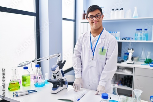 Down syndrome man wearing scientist uniform standing at laboratory