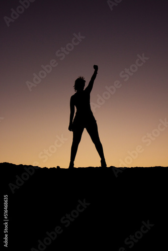 silueta de una mujer levantando el pu  o como victoria