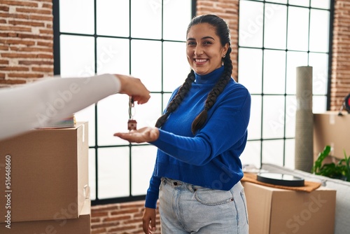 Young hispanic woman smiling confident reciving key of new house at new home photo