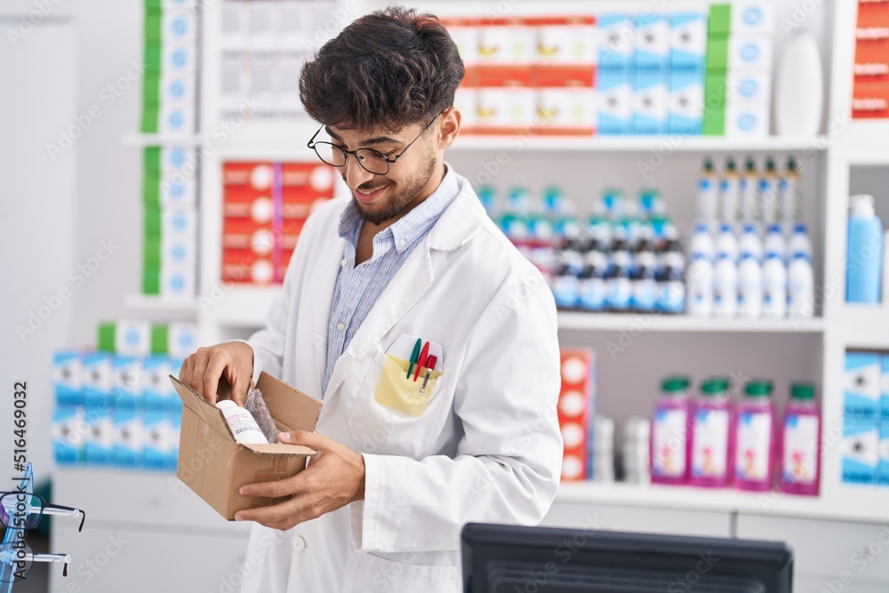 Young arab man pharmacist smiling confident unpacking cardboard box at pharmacy Young arab man pharmacist smiling confident unpacking cardboard box at pharmacy