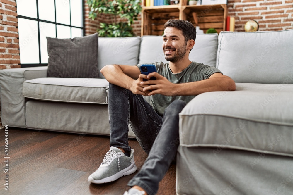 Young hispanic man smiling confident using smartphone at home