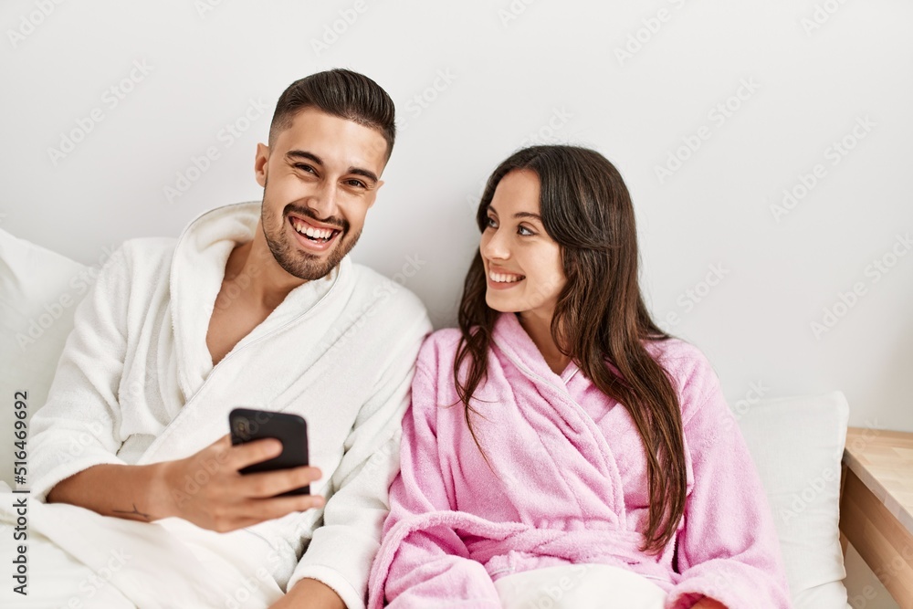 Young hispanic couple using smartphone lying on bed at home. Young hispanic couple using smartphone lying on bed at home.