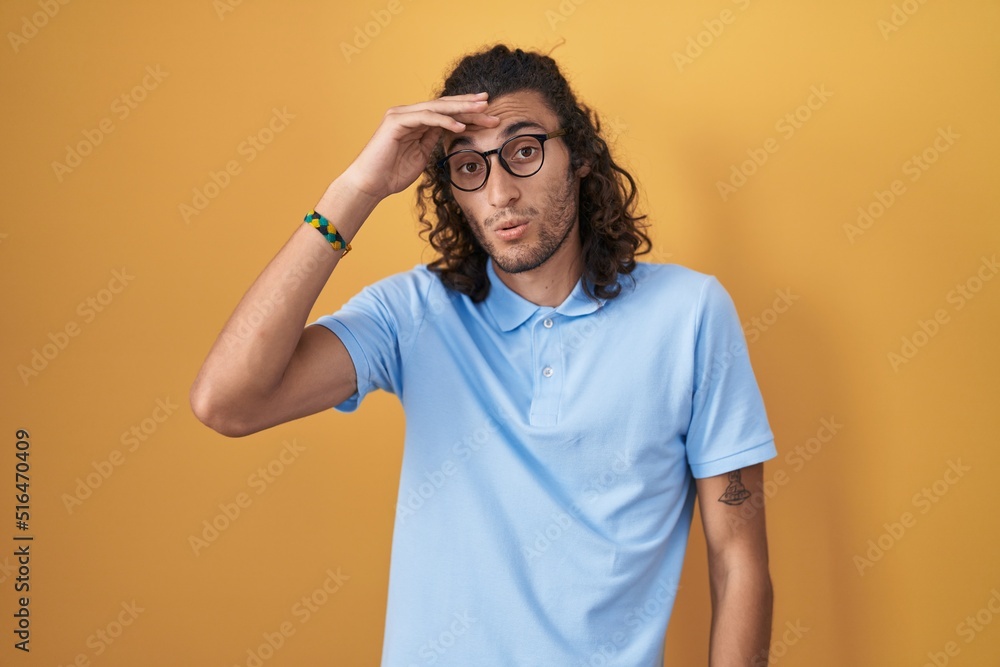 Young hispanic man standing over yellow background worried and stressed about a problem with hand on forehead, nervous and anxious for crisis Young hispanic man standing over yellow background worried and stressed about a problem with hand on forehead, nervous and anxious for crisis