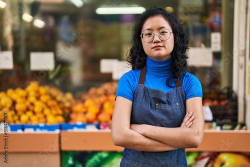 Young chinese woman employee standing with arms crossed gesture at fruit store © Krakenimages.com