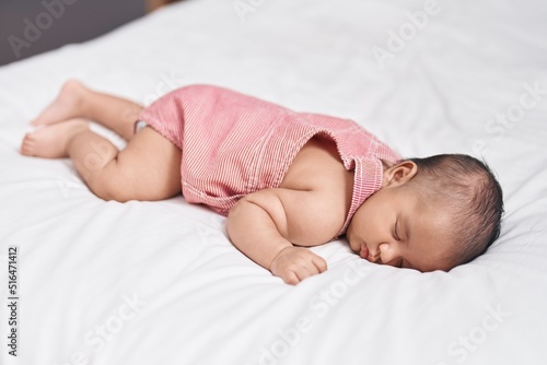 Adorable infant lying on bed sleeping at bedroom