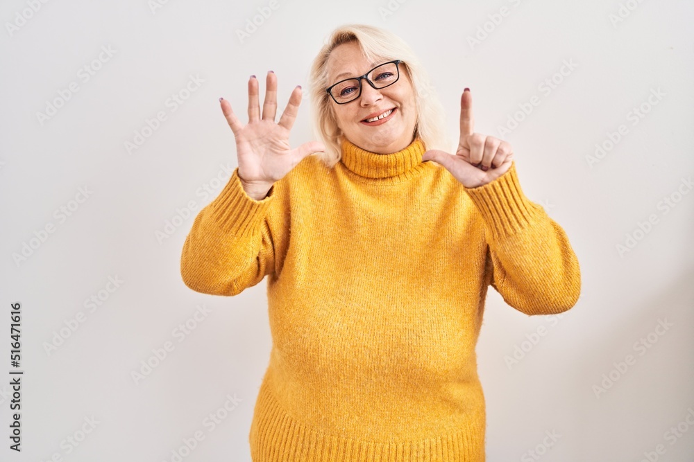 Naklejka premium Middle age caucasian woman wearing glasses standing over background showing and pointing up with fingers number seven while smiling confident and happy.