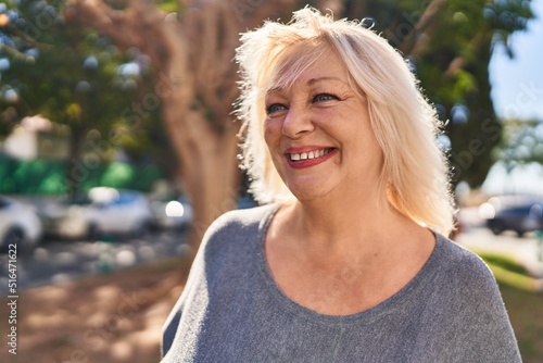 Middle age blonde woman smiling confident standing at park