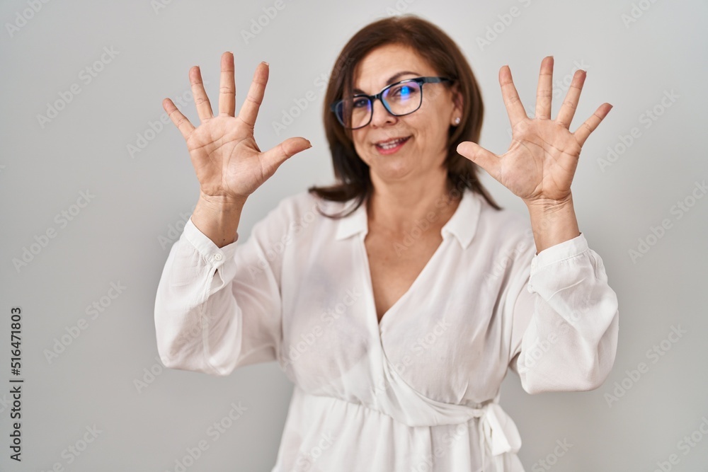 Middle age hispanic woman standing over isolated background showing and pointing up with fingers number ten while smiling confident and happy. Middle age hispanic woman standing over isolated background showing and pointing up with fingers number ten while smiling confident and happy.
