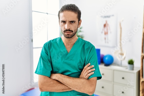 Young physiotherapist working at pain recovery clinic skeptic and nervous, disapproving expression on face with crossed arms. negative person.