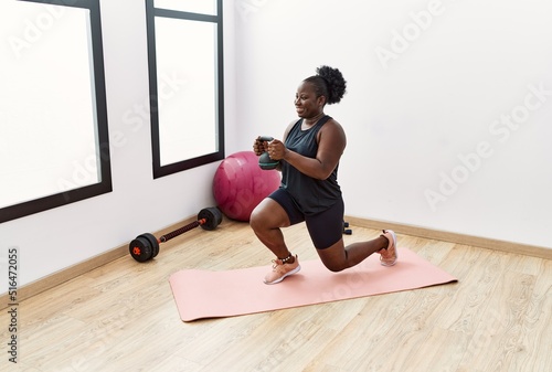 Young african american woman smiling confident training using dumbbell at sport center