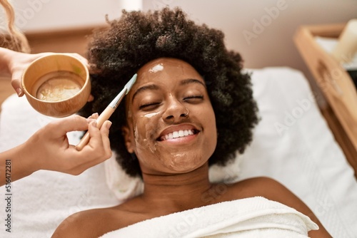 Young african american woman smiling confident having facial treatment at beauty center photo