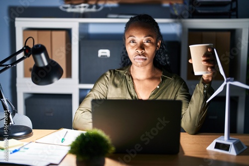 African woman working using computer laptop at night skeptic and nervous, frowning upset because of problem. negative person.