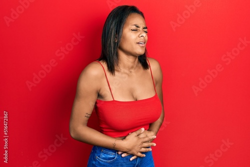 Young african american girl wearing casual style with sleeveless shirt with hand on stomach because nausea, painful disease feeling unwell. ache concept.