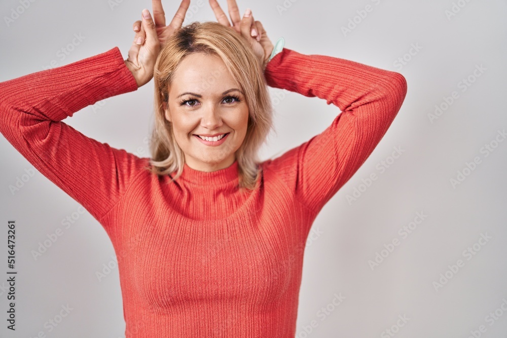 Blonde woman standing over isolated background posing funny and crazy with fingers on head as bunny ears, smiling cheerful Blonde woman standing over isolated background posing funny and crazy with fingers on head as bunny ears, smiling cheerful