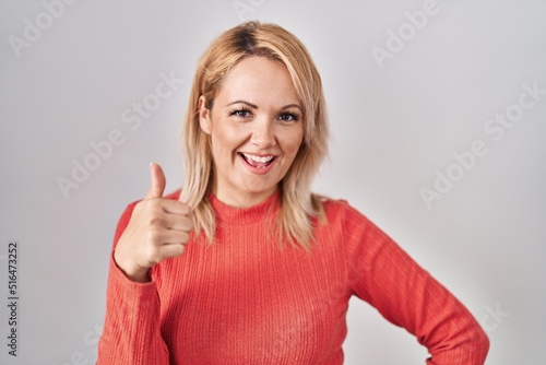 Wallpaper Mural Blonde woman standing over isolated background doing happy thumbs up gesture with hand. approving expression looking at the camera showing success. Torontodigital.ca