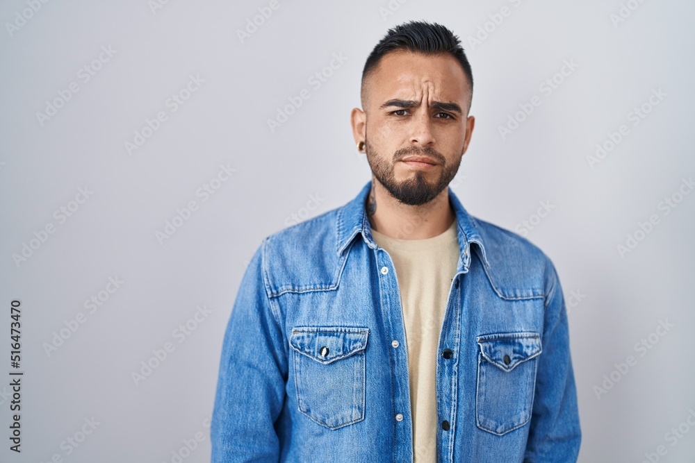 Young hispanic man standing over isolated background skeptic and nervous, frowning upset because of problem. negative person. Young hispanic man standing over isolated background skeptic and nervous, frowning upset because of problem. negative person.