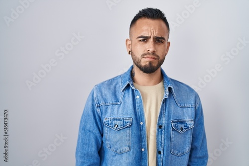 Young hispanic man standing over isolated background skeptic and nervous, frowning upset because of problem. negative person. © Krakenimages.com
