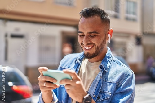 Young hispanic man smiling confident watching video on smartphone at street