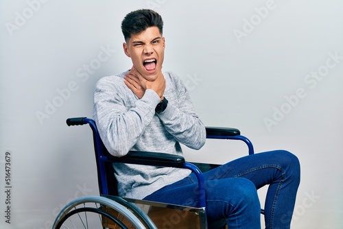 Young hispanic man sitting on wheelchair shouting suffocate because painful strangle. health problem. asphyxiate and suicide concept.