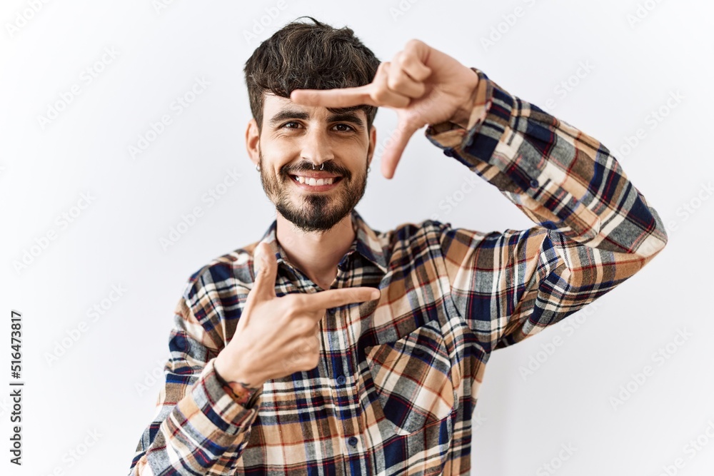 Hispanic man with beard standing over isolated background smiling making frame with hands and fingers with happy face. creativity and photography concept. Hispanic man with beard standing over isolated background smiling making frame with hands and fingers with happy face. creativity and photography concept.