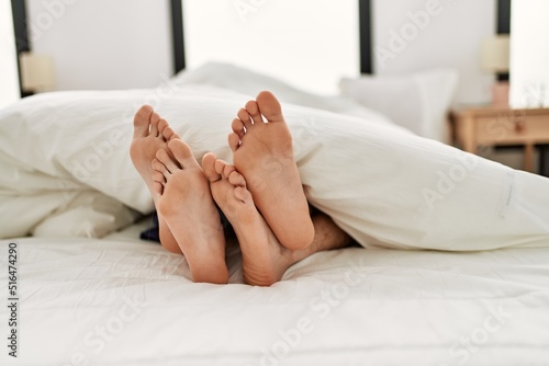 Couple feet under sheets on the bed at home.