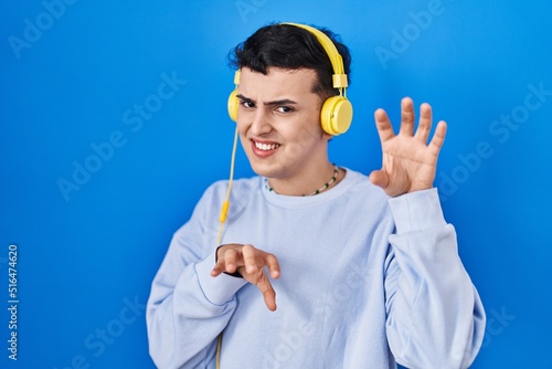 Non binary person listening to music using headphones smiling funny doing claw gesture as cat, aggressive and sexy expression photo