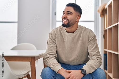 Young arab man smiling confident sitting on chair at home