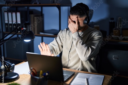 Young handsome man working using computer laptop at night covering eyes with hands and doing stop gesture with sad and fear expression. embarrassed and negative concept.
