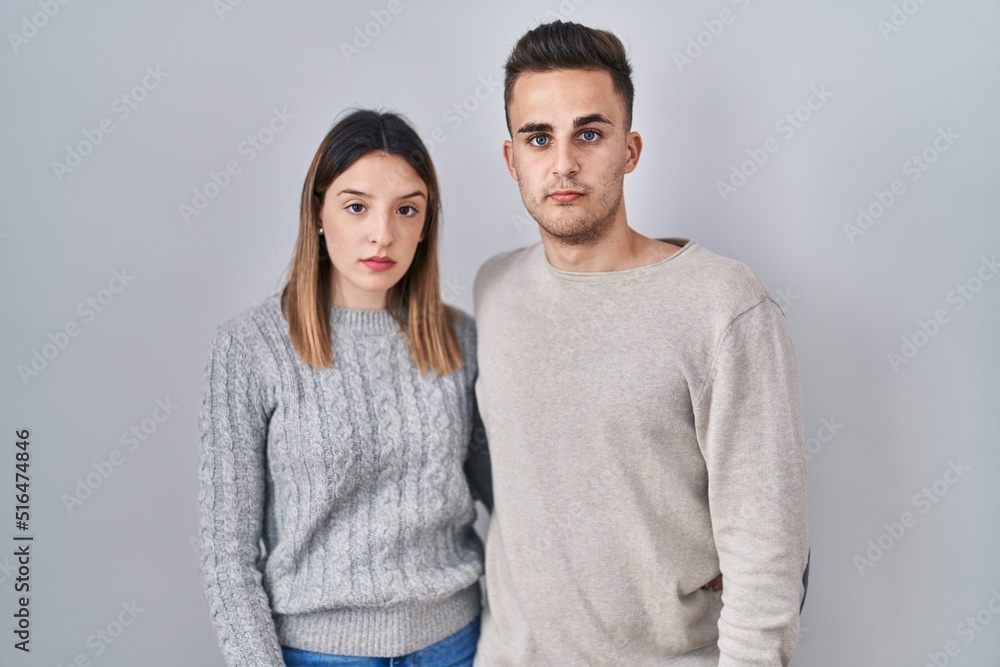 Young hispanic couple standing over white background relaxed with serious expression on face. simple and natural looking at the camera. Young hispanic couple standing over white background relaxed with serious expression on face. simple and natural looking at the camera.