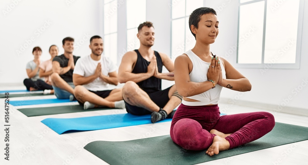 Naklejka premium Group of young hispanic people smiling happy training yoga at sport center.
