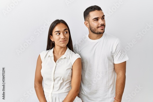 Young interracial couple standing together in love over isolated background smiling looking to the side and staring away thinking.