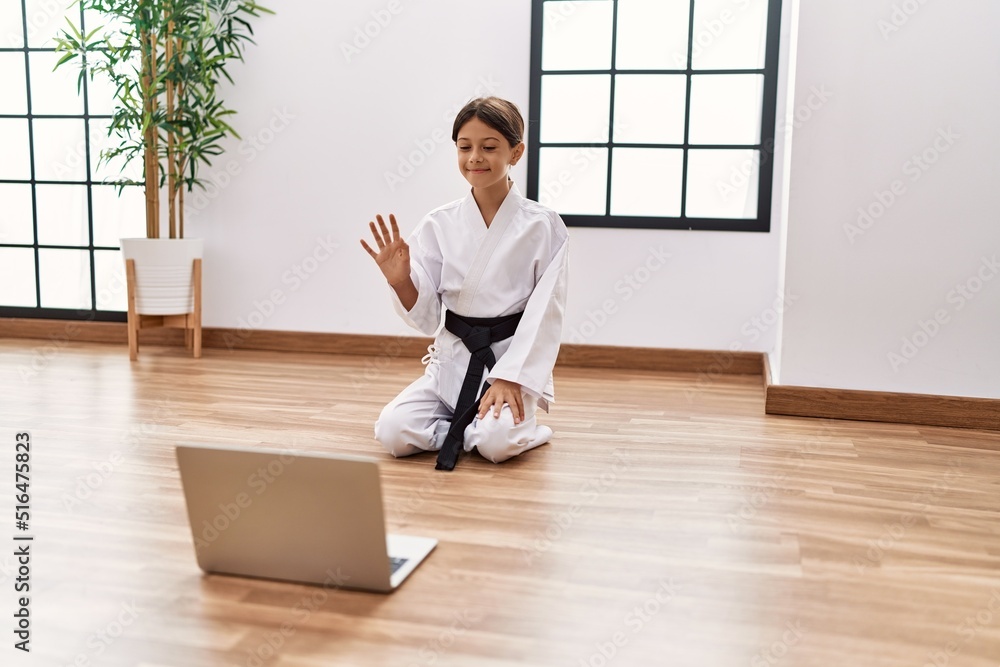 Young hispanic girl doing martial arts looking at tutorial at training studio Young hispanic girl doing martial arts looking at tutorial at training studio