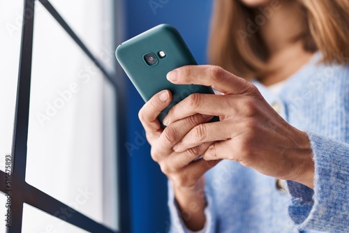 Young woman using smartphone standing at home