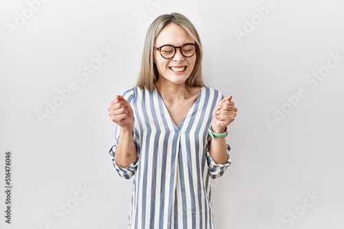 Asian young woman wearing casual clothes and glasses excited for success with arms raised and eyes closed celebrating victory smiling. winner concept.