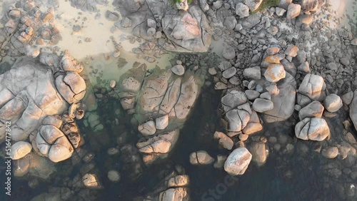 Large stones dot the coastal landscape of the beach in Galicia, Spain.  Coastal beauty up and down the shoreline as shown by this spinning upward traveling aerial photo