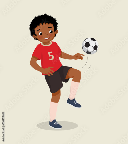 cute little African boy playing soccer practicing kicking the football with his knee