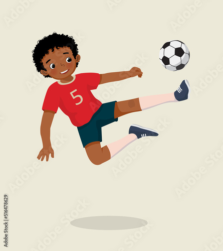 cute little African boy playing soccer jumping high kicking the football to make a goal