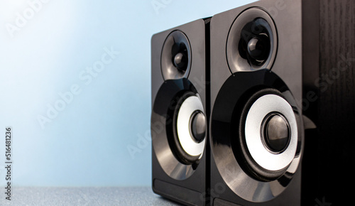 Black glossy music speakers on a blue background with place for text.Music speakers concept.