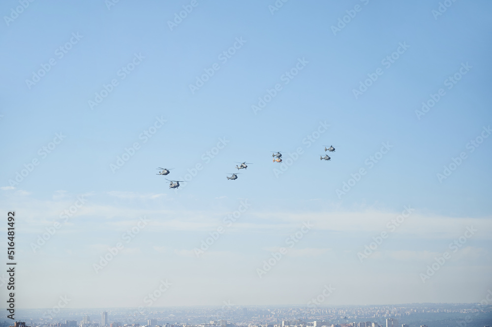 Group of helicopters specialized in war missions flying in formation during an exhibition of the air force with the blue sky as background.