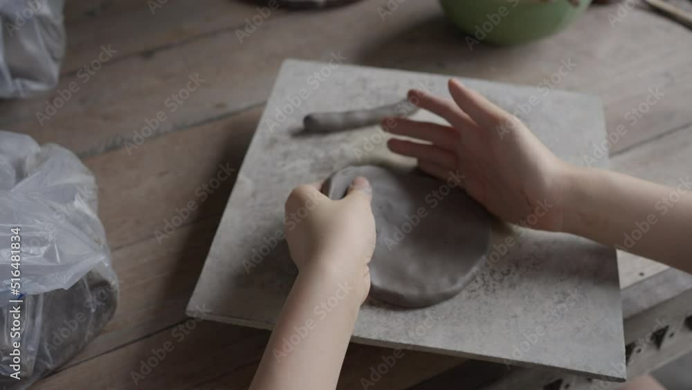 Close up of female teenager's hands making clay pottery with basic pottery tools Close up of female teenager's hands making clay pottery with basic pottery tools