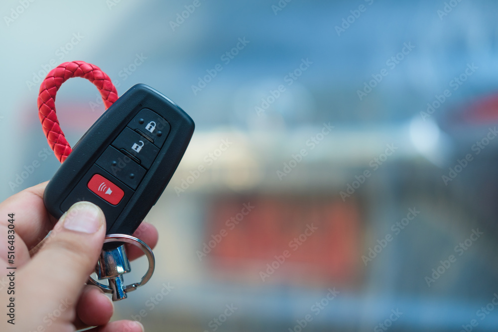 Human hand holding remote control car key with red keychain