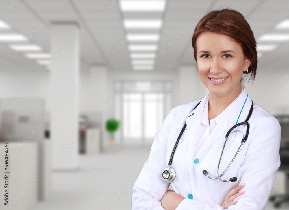 Young happy doctor standing on hospital background Young happy doctor standing on hospital background