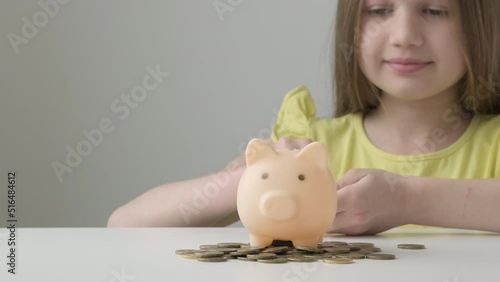 Provident economical little girl child put money into piggy bank saving for future needs. Savings, budget planning. Happy smart small 9s teen kid make donation contribution in piggybank. Copy space photo