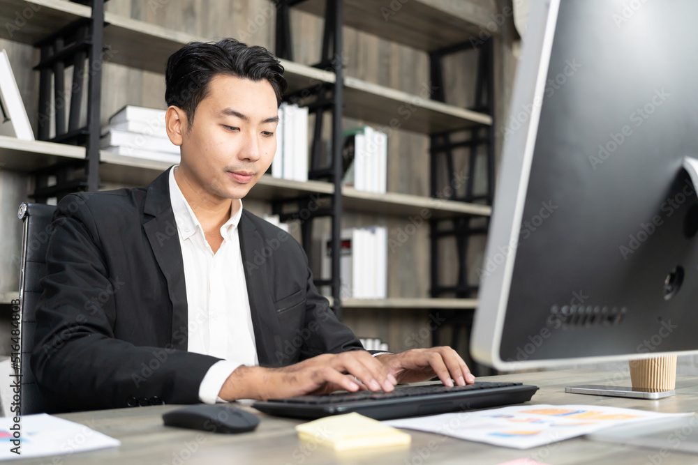 Portrait of business man using computer at workplace in an office. positive business man smiling looking into screen of computer. Portrait of business man using computer at workplace in an office. positive business man smiling looking into screen of computer.
