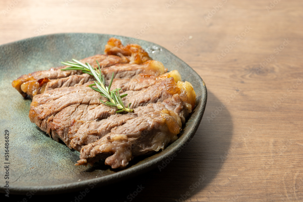 delicious roast beef, on a black plate and wooden surface, with a sprig of thyme on top. copy space delicious roast beef, on a black plate and wooden surface, with a sprig of thyme on top. copy space