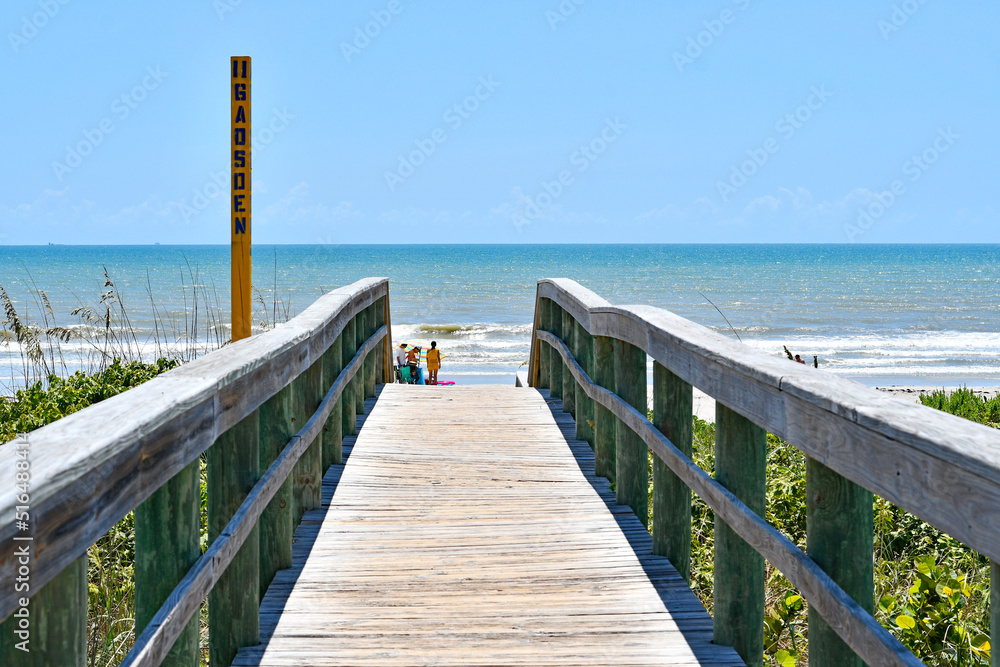 Obraz premium Wooden board walkway over the dunes to the beach in Cocoa Beach near Cape Canaveral, Florida
