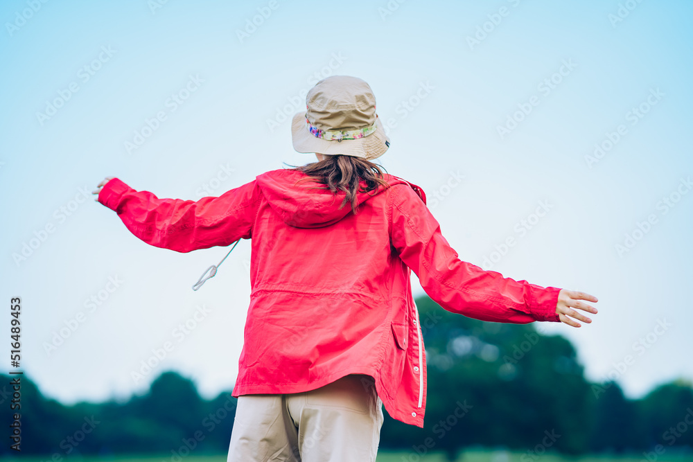 草原で深呼吸をする女性の後ろ姿