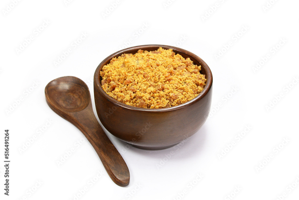 Jaggery Sugar Cane Powder in a wooden bowl with wooden spoon isolated on white background Jaggery Sugar Cane Powder in a wooden bowl with wooden spoon isolated on white background